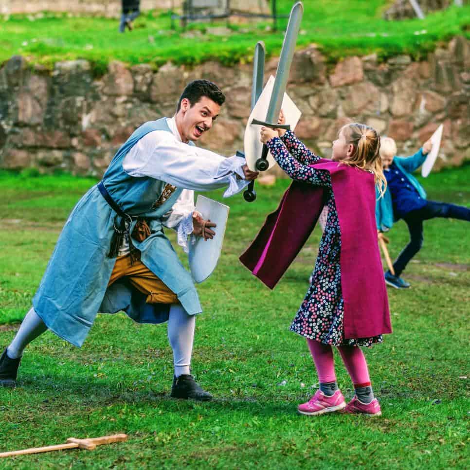 A child fences and plays knight school with staff during a children's party at Bohus fortress